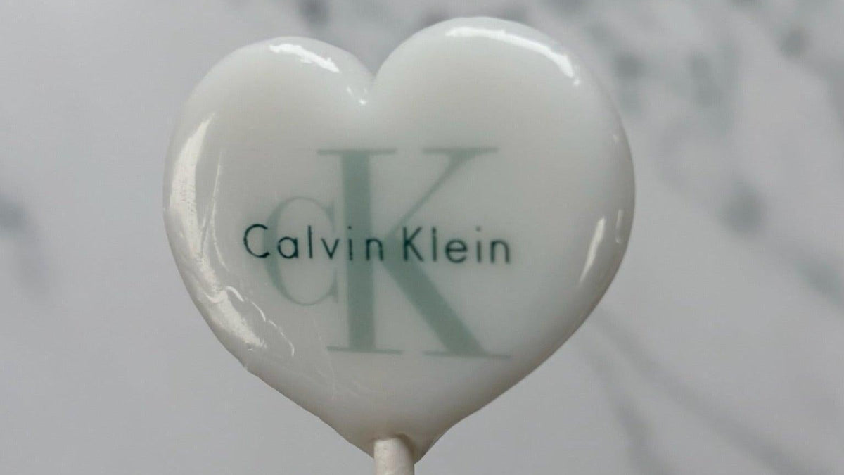 Heart-shaped lollipop with Calvin Klein logo on a marble background