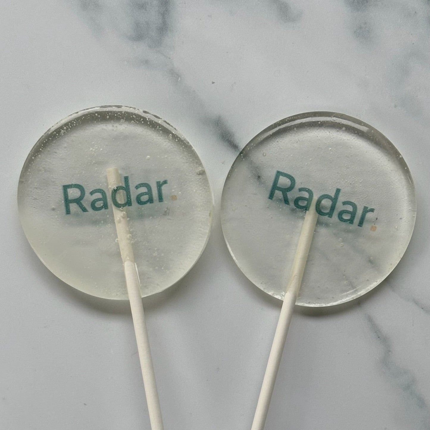 Two lollipops with 'Radar' branding on a marble surface
