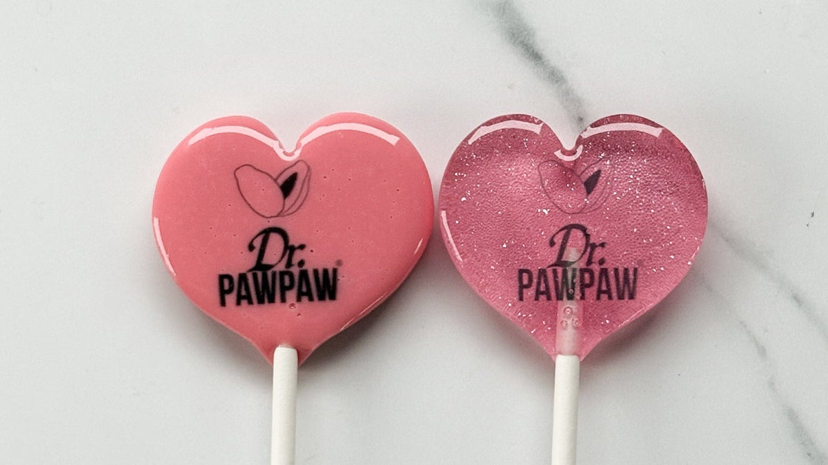 Two heart-shaped lollipops with 'Dr. Pawpaw' branding on a marble surface.